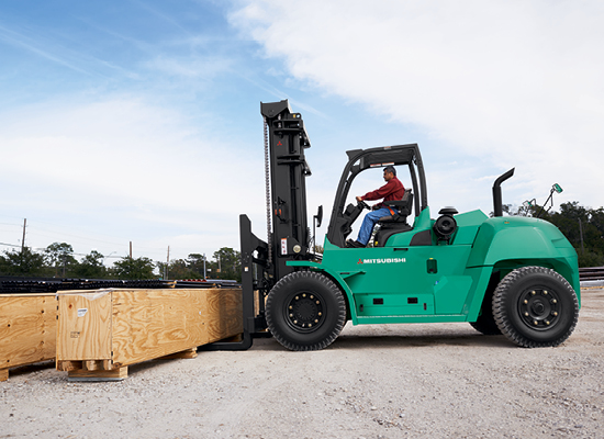 A Mitsubishi FD100N Picking Up a Large Load Outdoors