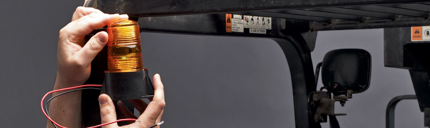 Closeup of a Technician Fixing a Light onto a CAT Forklift Carriage