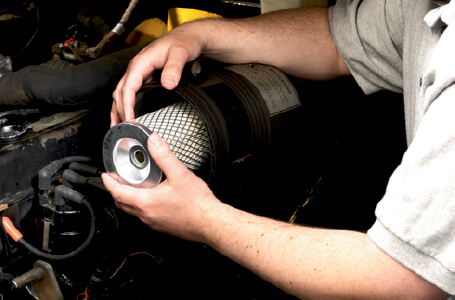 Worker providing maintenance on forklift engine