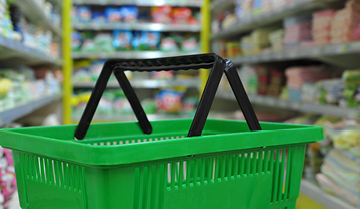 Green shopping basket in grocery store aisle