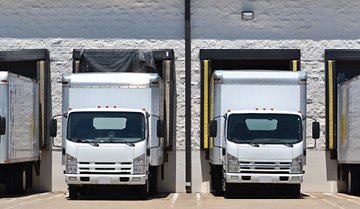 Two loading trucks in garages parked next to each other