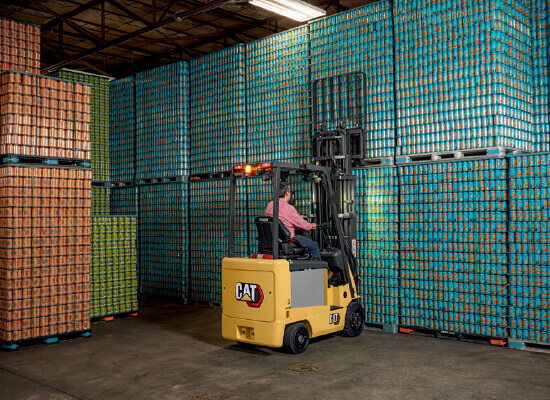 Worker lifting large pallet with Cat small electric cushion forklift 