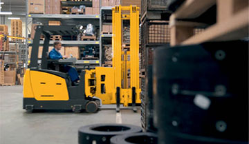 Worker driving Jungheinrich man-down turret truck down the aisle