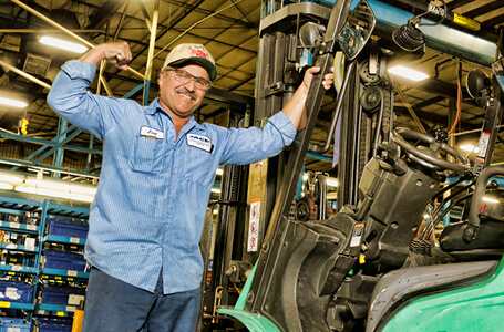 MCFA employee next to forklift flexing arm muscle