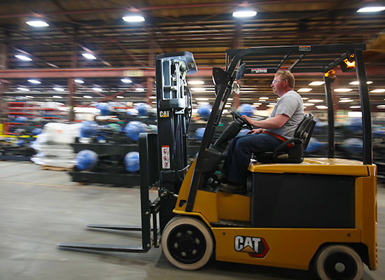 Cat lift trucks electric cushion tire mid-size forklift traveling to the left inside warehouse