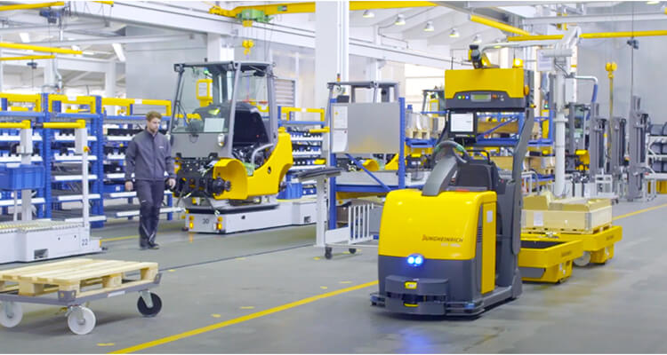 jungheinrich automated tow tractor towing carts in warehouse
