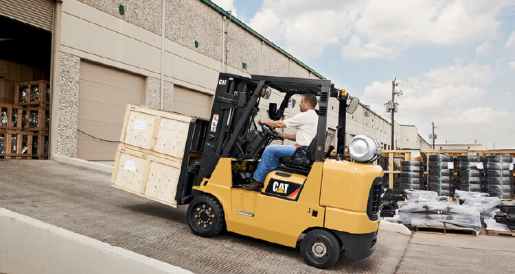 Worker driving a Cat lift truck up ramp