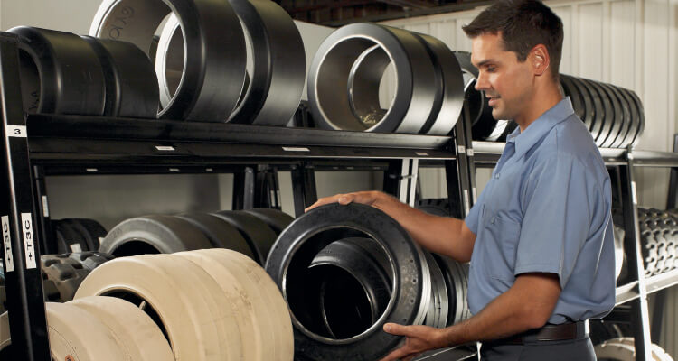 Man picking forklift tires off a shelf