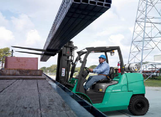 Operator loading metal bars on semi-truck with FG40N