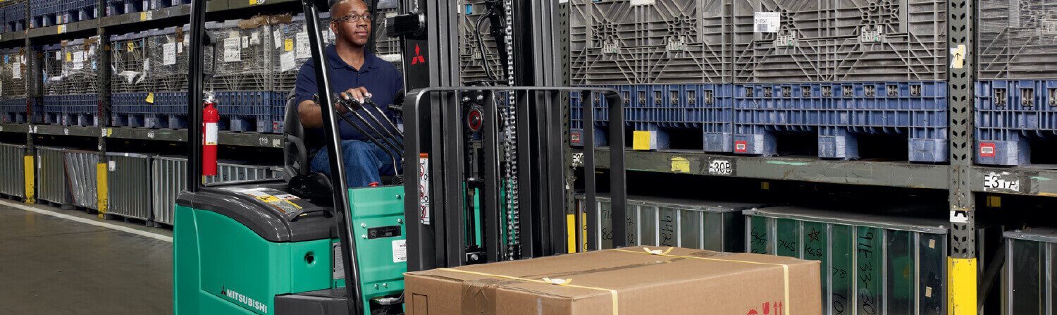 Operator moving cardboard box with Mitsubishi forklift truck