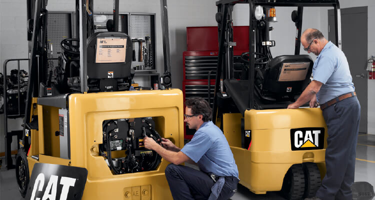 Two workers repairing the backs of different Cat forklifts