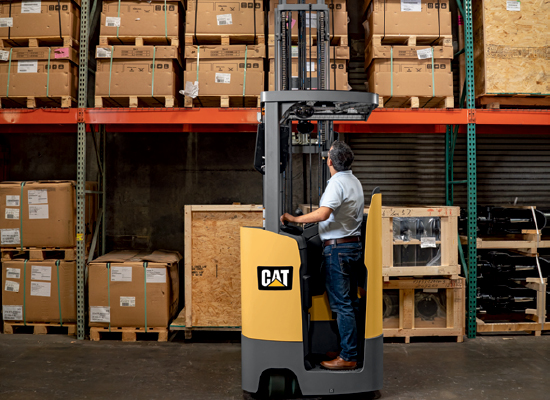 Operator Using a Cat Stand-Up Counterbalanced Forklift to Load Pallets onto Shelves