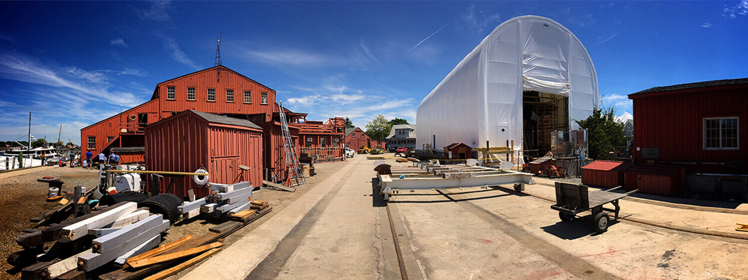 Mystic seaport worksite with warehouses, tents and ship materials