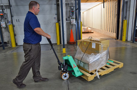 Man pulling Mitsubishi hand pallet truck loaded with boxes